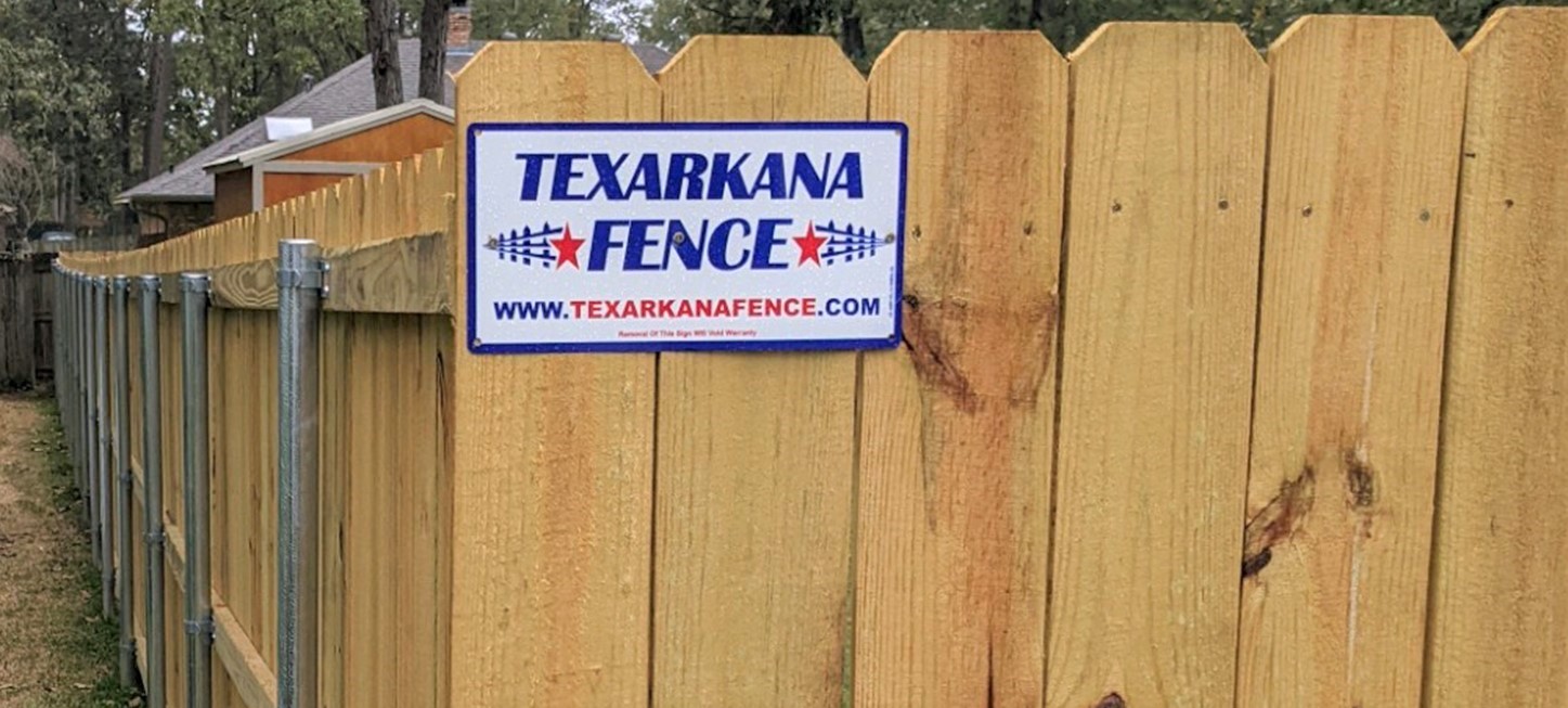 Photo of a wooden fence installed with Texarkana Fence sign